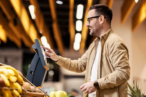 Homem em mercado, realizando compras na tela mostrando que não diferencia a experiência digital e física.