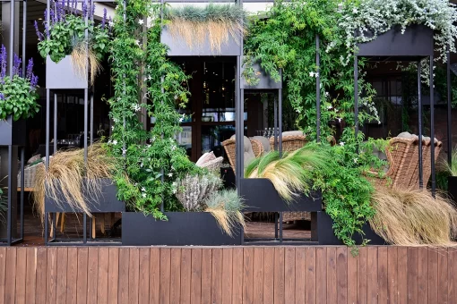 Restaurante com bela vista externa e paisagismo - arquitetura de comércios. Espaço confortável e piso em madeira escura.