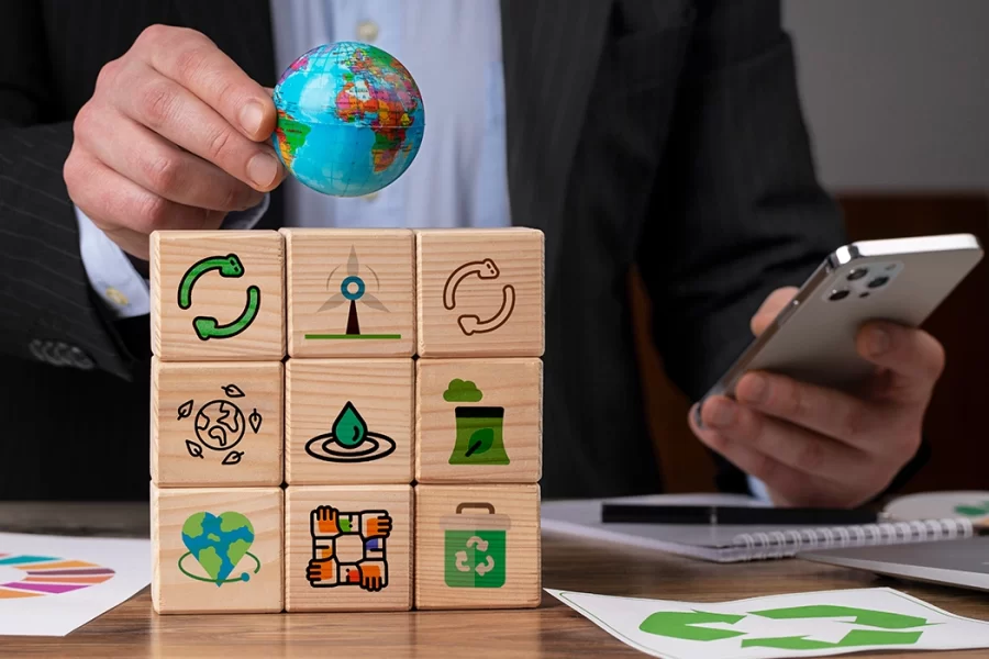 empresário com celular e blocos de madeiras com imagens coloridas, representando a sustentabilidade