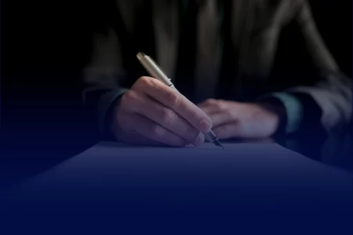 Pessoa assinando contrato. A legenda informa o quão é importante estar amparado de ajuda profissional ao assinar um contrato de locação comercial.