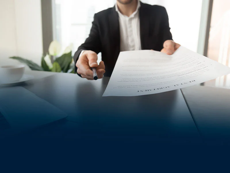 Imagem mostrando pessoa entregando contrato assinado, mostrando a importância de ler minuciosamente o contrato antes de alugar um imóvel comercial